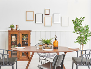 Wooden dining room close up and wooden cabinet in the white wall. Many frame on the wall.