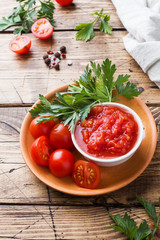 Tomato sauce pasta in a bowl and fresh tomatoes with parsley on a wooden table