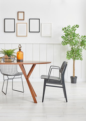 Vertical wooden table dining room style, chair frame and vase of plant.