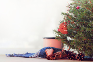 mug with a scarf and biscuits stands on the table under the Christmas tree  warming atmosphere of...