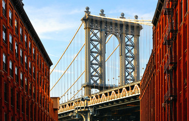 Obraz premium Manhattan Bridge and red brick wall old buildings and architectures with windows and blue cloudy sky in Brooklyn in DUMBO district, Manhattan, New York City, USA
