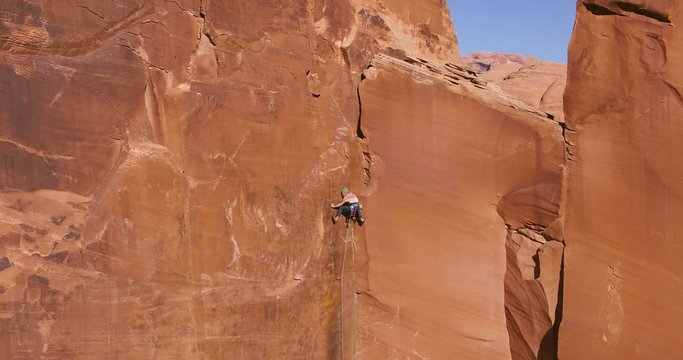 Man rock climbing extreme vertical wall reaching for top 