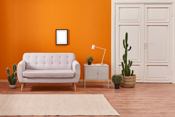 Orange living room, sofa and cupboard, white lamp with many cactus style with carpet.