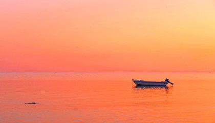 Naklejka premium a peaceful sea with warm sunset colors and a solitary boat in a beach near Agrigento in Sicily Italy