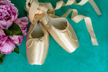 Pink pointes with ribbons and flowers. Spring ballet shoes with roses on the background. Vintage...