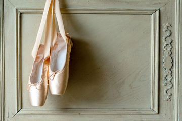 Pink pointes with ribbons and flowers. Spring ballet shoes with roses on the background. Vintage background. Soft light. Copy space © Anna