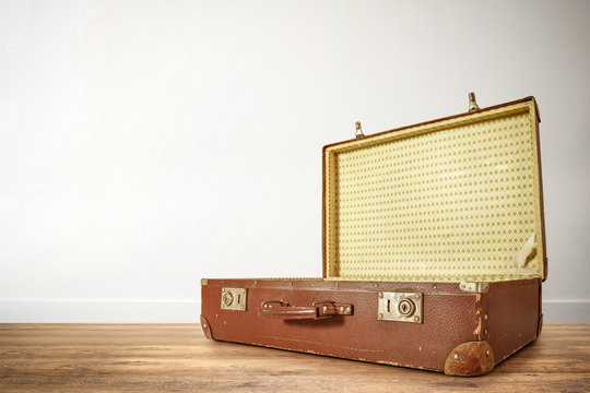 Retro old brown suitcase on the floor and white empty wall background of free space for your decoration. 