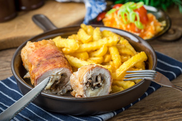 Fried chicken breast stuffed with mushrooms and cheese wrapped in ham served with fries and salad.