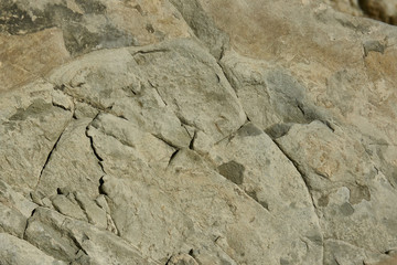 Mountain stone with a natural texture as a design concept. Cracks created by nature on the surface of the stone with a natural color scheme, create a natural textured background. Texture for design .