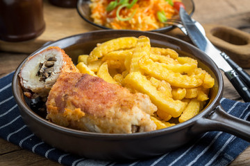 Fried chicken breast stuffed with mushrooms and cheese wrapped in ham served with fries and salad.