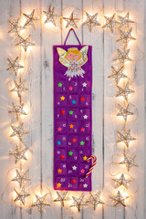 A border of golden star christmas lights, with a advent calander, on a destressed woodern background