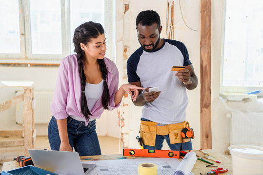 Happy Young Couple Making E-shopping During Renovation Of Home