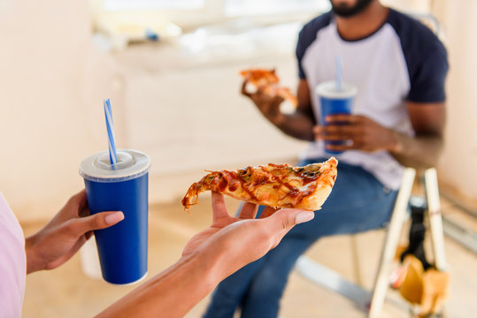 cropped image of couple having lunch with pizza and soda during renovation