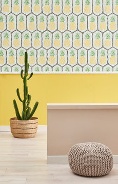 Pineapple room, vase of plant and grey puff style interior.