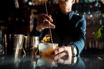 Fototapeta na wymiar The bartender strains a cocktail in a glass at a nightclub, beach, pub, restaurant