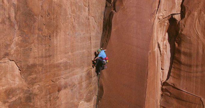 Aerial view of extreme rock climber topping out on multi pitch climb 