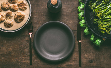 Empty plate with cutlery and low carb dieting meal with meat balls, blanched broccoli in cooking pan and measure tape on wooden table background, top view with copy space. Healthy weight loss diet
