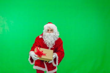 Merry Christmas. Santa Claus in a red suit gives out gifts in boxes on a green screen background chroma key