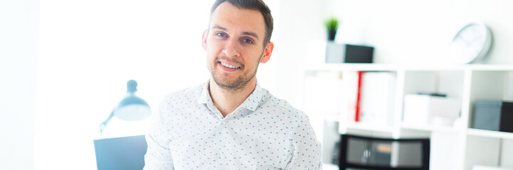 Obraz premium A young man stands leaning on a table in the office.