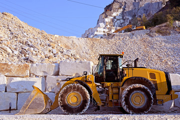 Marble quarry with a yellow bulldozer end marble blocks end debris
