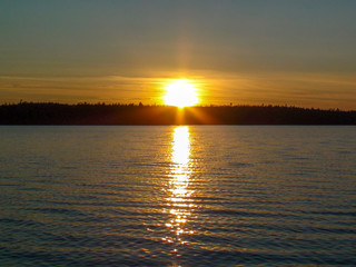 Naklejka premium Orange sunset and glowing path on the lake in Karelia