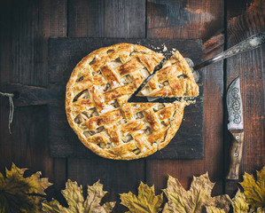 classic American apple pie with puff pastry on an old brown kitchen board