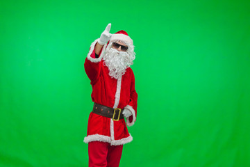 Modern Santa Claus in sunglasses over green background. Christmas