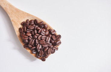 Many coffee beans in the wood spoon and white background.