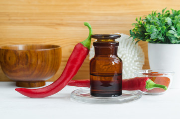 Pharmacy bottle with  red chili pepper extract (tincture, infusion, oil) and fresh chili pepper pods. Baldness, alopecia natural remedy and pain relief. Copy space.  