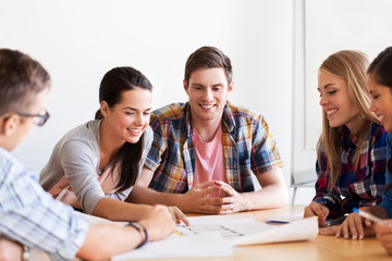Fototapeta premium education, architecture and people concept - group of smiling students with blueprint meeting indoors