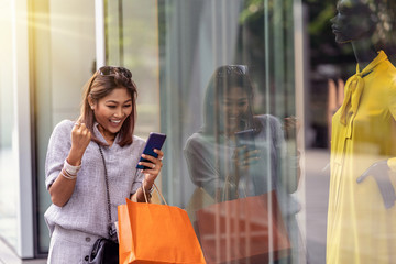 Asian woman cheerful when using the smart mobile phone for check online shopping order is completed...