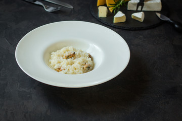 risotto with mussels (seafood rice) in a white plate and a glass of white wine on a dark background