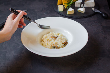 risotto with mussels (seafood rice) in a white plate and a glass of white wine on a dark background