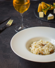 risotto with mussels (seafood rice) in a white plate and a glass of white wine on a dark background