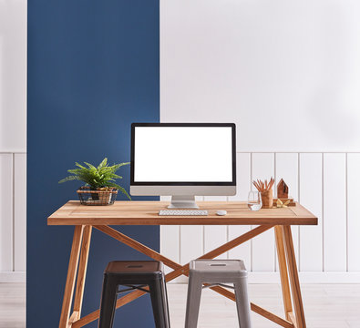 Computer on the wooden table. Metal black and grey chair. Blue banner wall and white background room.