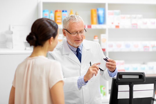 medicine, pharmaceutics, healthcare and people concept - senior apothecary with drug and female customer at pharmacy