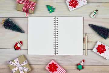 Christmas and new year's resolution, a blank white notebook with wooden pencil on light wood table with Christmas ornaments