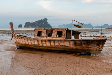 An old wooden boat at low tide at sunset on a tropical island (Koh Yao Noi, Thailand)