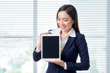Smiling asian businesswoman in bright office using digital tablet.
