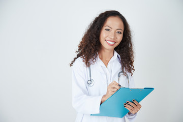 Confident Asian woman doctor standing in white gown and taking notes on a clipboard