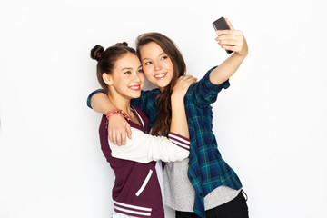 Naklejka premium technology and friendship concept - happy smiling pretty teenage girls taking selfie by smartphone over white background