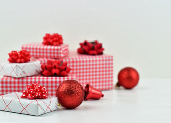 Obraz na płótnie Canvas Red and white Christmas and New Year gift boxes and Christmas ornaments on white wooden table and white background with and copy space for text, festive and celebration concept