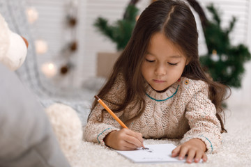 Cute child girl writing letter to Santa Claus at home