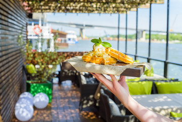 Close up hand holds Belgian waffles on tray