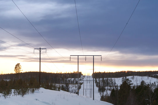 Winter_landscape_at_dusk_with_power_lines_leading_to_to_the_far_distant_surrounded_by_conifer_forest_and_clear-cut_in_snowy_valley