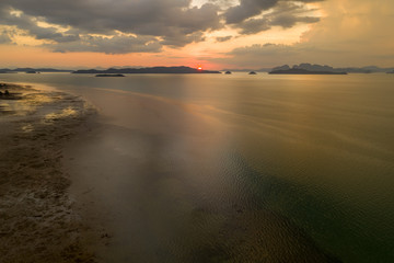Aerial view of a colorful tropical sunset over a beach and calm ocean