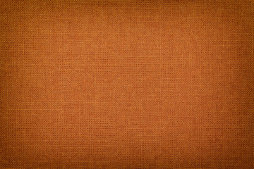 Orange background from a textile material with wicker pattern, closeup.
