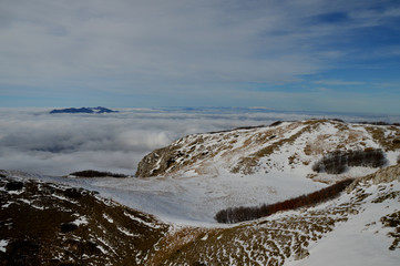 Trekking on the snow-covered mountain ends above a cloud-covered sky