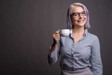 Young beautiful businesswoman with short colorful hair against g