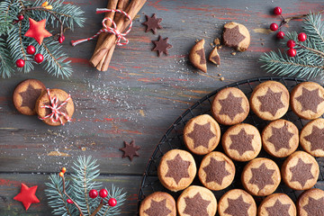 Christmas cookies with chocolate star pattern on cooling rack with spices and decorated fir twigs